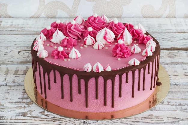 Roze crème cakeschuimgebakjes met vlekken van chocolade op een witte houten achtergrond Premium Foto