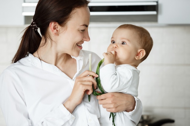 Schattige Baby En Haar Moeder Groene Ui Eten Gratis Foto