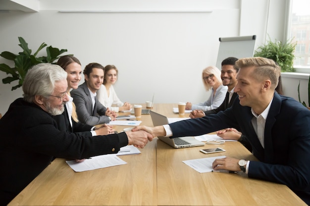 Senior investeerder kopen opstarten handshaking jonge ondernemer op groepsbijeenkomst Gratis Foto