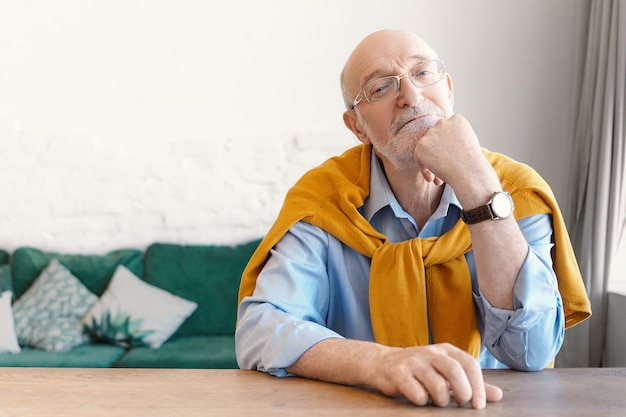 Senior kale man psycholoog in rechthoekige bril en trui vastgebonden