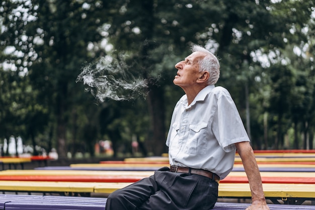 Walging neutrale Ritueel Senior volwassen mannen roken sigaret buiten in het stadspark wanneer ze op  de bank zitten. | Premium Foto