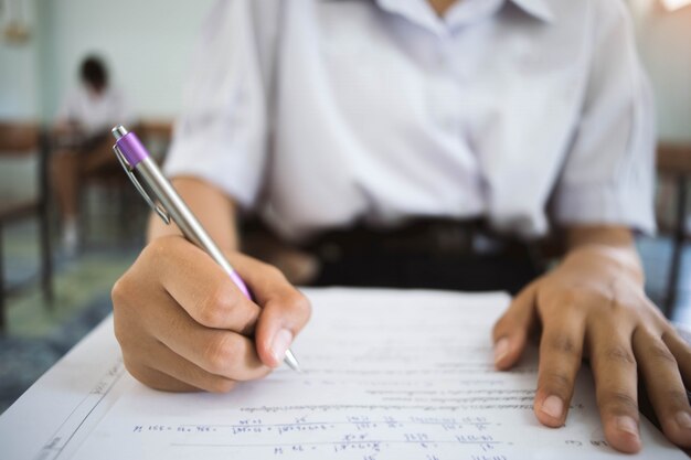 Sluit student omhoog het lezen en het schrijven examen met spanning in klaslokaal. Premium Foto