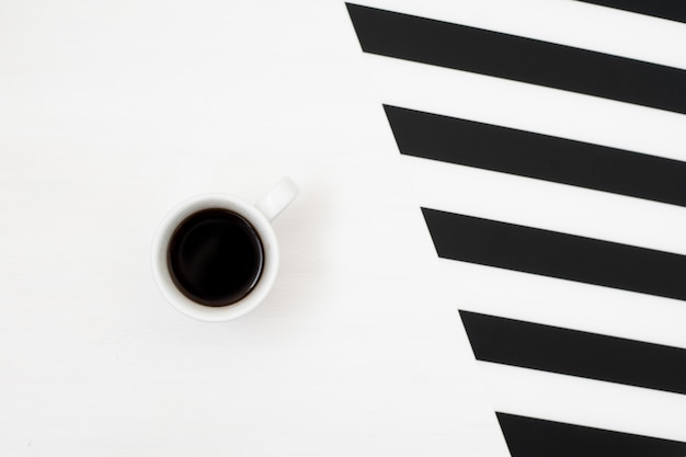 Stijlvolle minimalistische werkruimte met kopje koffie op gestreepte achtergrond Premium Foto