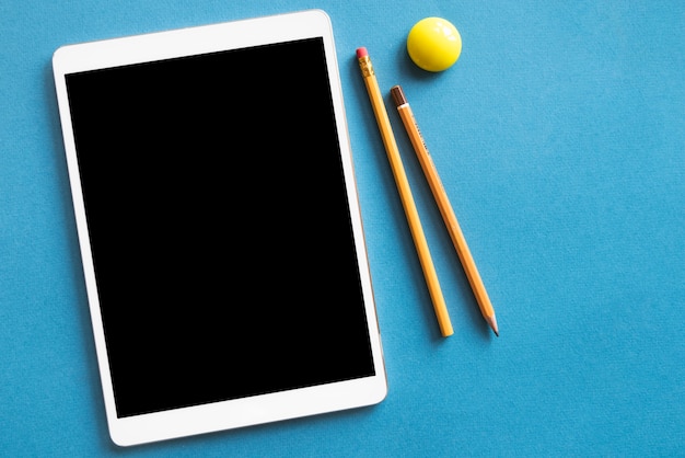 Tablet en potloden op blauwe oppervlak Gratis Foto