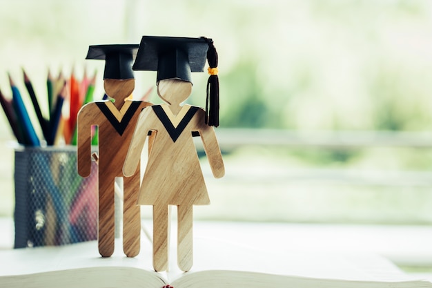 Terug naar school concept, twee mensen ondertekenen hout met afstuderen glb vieren op open leerboek Premium Foto