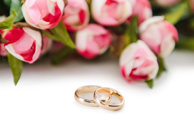 Trouwringen en bloemen op wit worden geïsoleerd dat Premium Foto