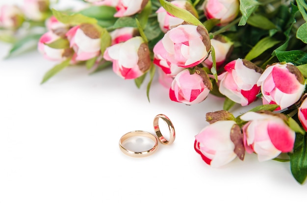 Trouwringen en bloemen op wit worden geïsoleerd dat Premium Foto