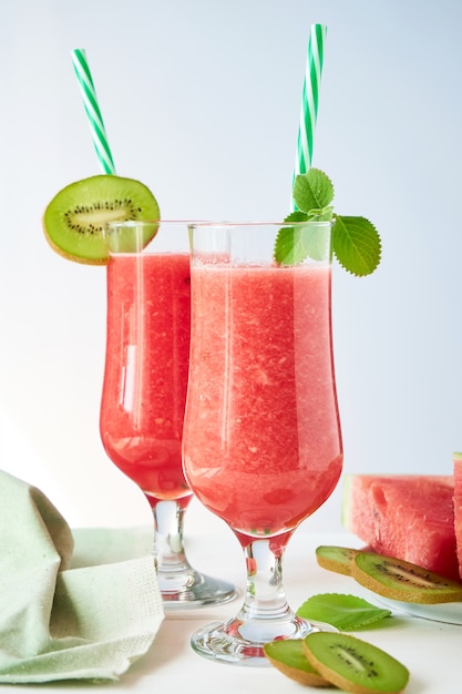 Twee glazen verse watermeloen smoothie met kiwi en munt op een witte lijst Premium Foto