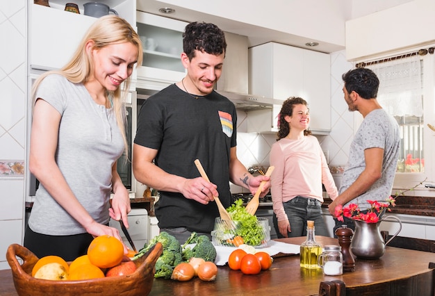 Twee jonge paren die samen voedsel in de keuken voorbereiden Gratis Foto