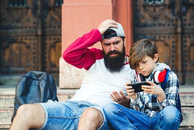 Vader en zoon gebruiken smartphones buitenshuis Premium Foto