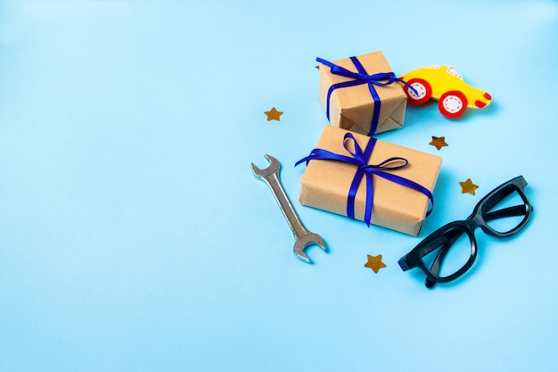 Vaderdag concept kaart met man's werk hulpmiddel op blauwe achtergrond en geschenken vakken verpakt in kraftpapier Premium Foto