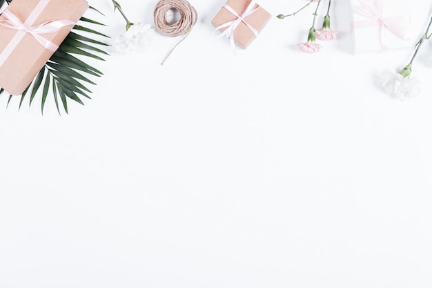 Vakken met geschenken, linten, touw en bloemen op witte tafel, bovenaanzicht Premium Foto
