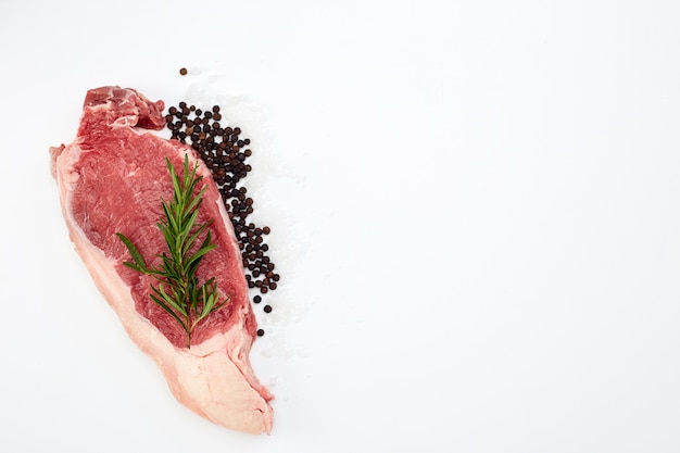 Vers ruw rundvleeslapje vlees met kruiden op wit Premium Foto