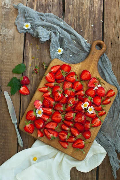 Verse aardbeien fruit, bloemen, bladeren op witte houten tafel Gratis