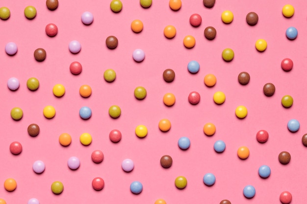 Volledig kader van kleurrijk multicolored gemsuikergoed op roze achtergrond Gratis Foto