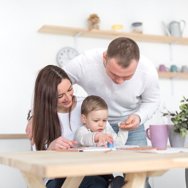 Vooraanzicht van gelukkige ouders met baby in de keuken Gratis Foto