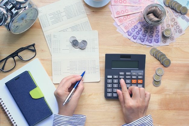 Vrouw die een calculator gebruikt en pennen op de lijst houdt Premium Foto
