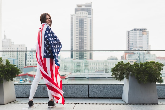 Vrouw die zich in helft-draai met de grote vlag van de vs bevindt Gratis Foto