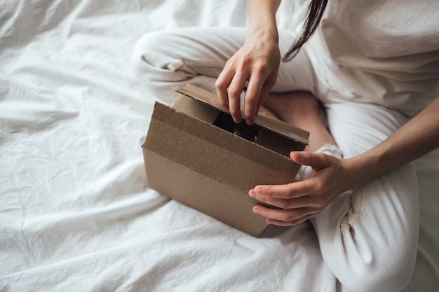 verwijderen spoor Passief Vrouw opent een kartonnen doos, het pakket zit thuis op het bed. levering  concept | Premium Foto