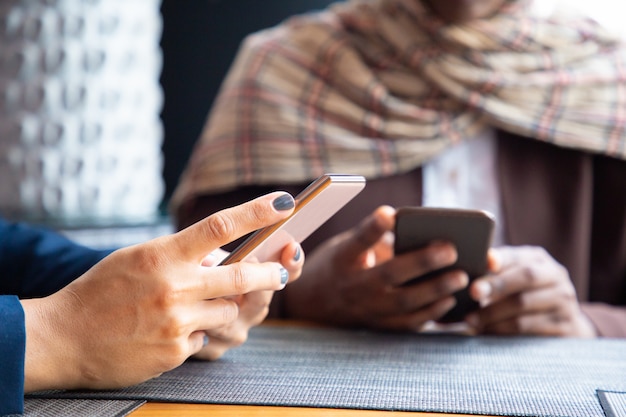 Vrouwelijke collega's die op telefoons in koffiewinkel babbelen