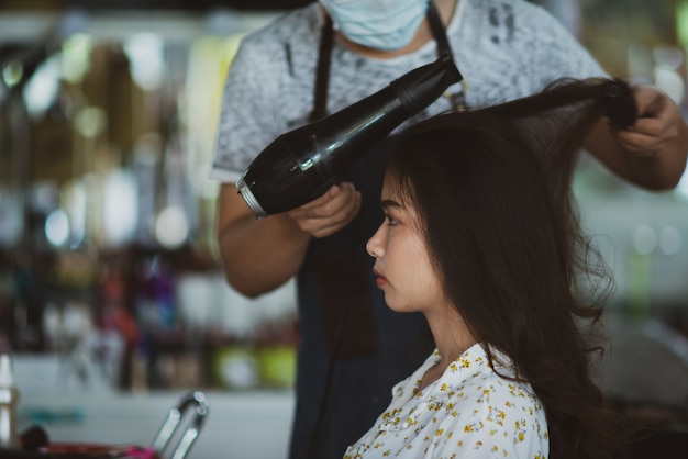 Vrouwelijke kapper permanent, gezicht make-up en het maken van kapsel tot schattige mooie jonge vrouw in schoonheidssalon Gratis Foto