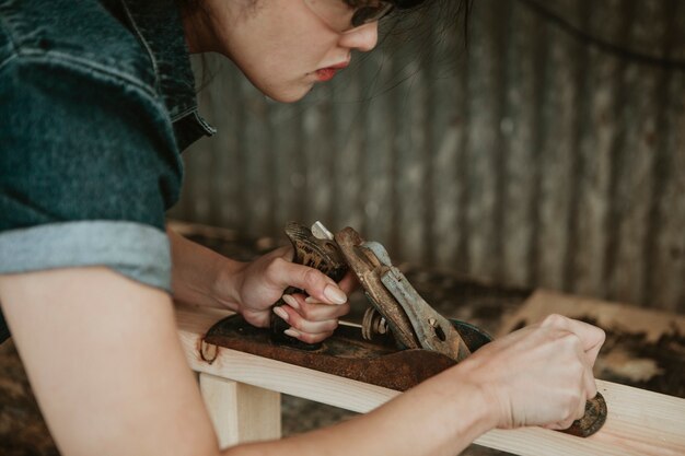 Vrouwelijke timmerman die hout vormt met een handschaaf Premium Foto