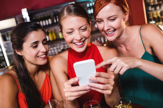 Vrouwelijke vrienden die mobiele telefoon met behulp van terwijl het genieten van van wijn Premium Foto