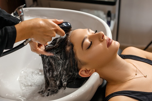 Wasprocedure. mooie jonge vrouw met het hoofd van de kapperwas bij haarsalon. Premium Foto