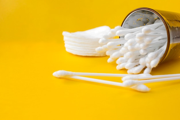 Wattenstaafjes en make-up schoonmakende schijven op een geel Premium Foto