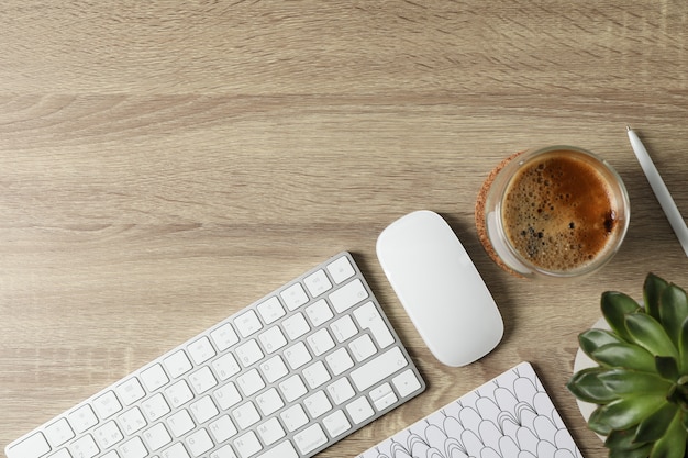 Werkplek. toetsenbord, muis, glas koffie en plant op houten tafel