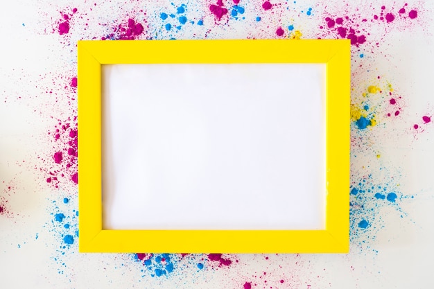 Wit leeg kader met gele grens op het poeder van de holikleur over witte achtergrond Gratis Foto