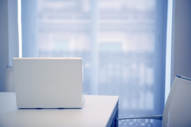 Witte laptop open op een witte ruimte, blauw licht dat uit venster komt Premium Foto