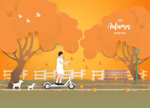 Een jonge jongen die een elektrische autoped in het park op het gras in de herfst berijdt. Premium Vector