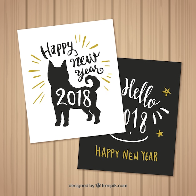 Set van twee hand getrokken kaarten van het nieuwe jaar met een hond Gratis Vector